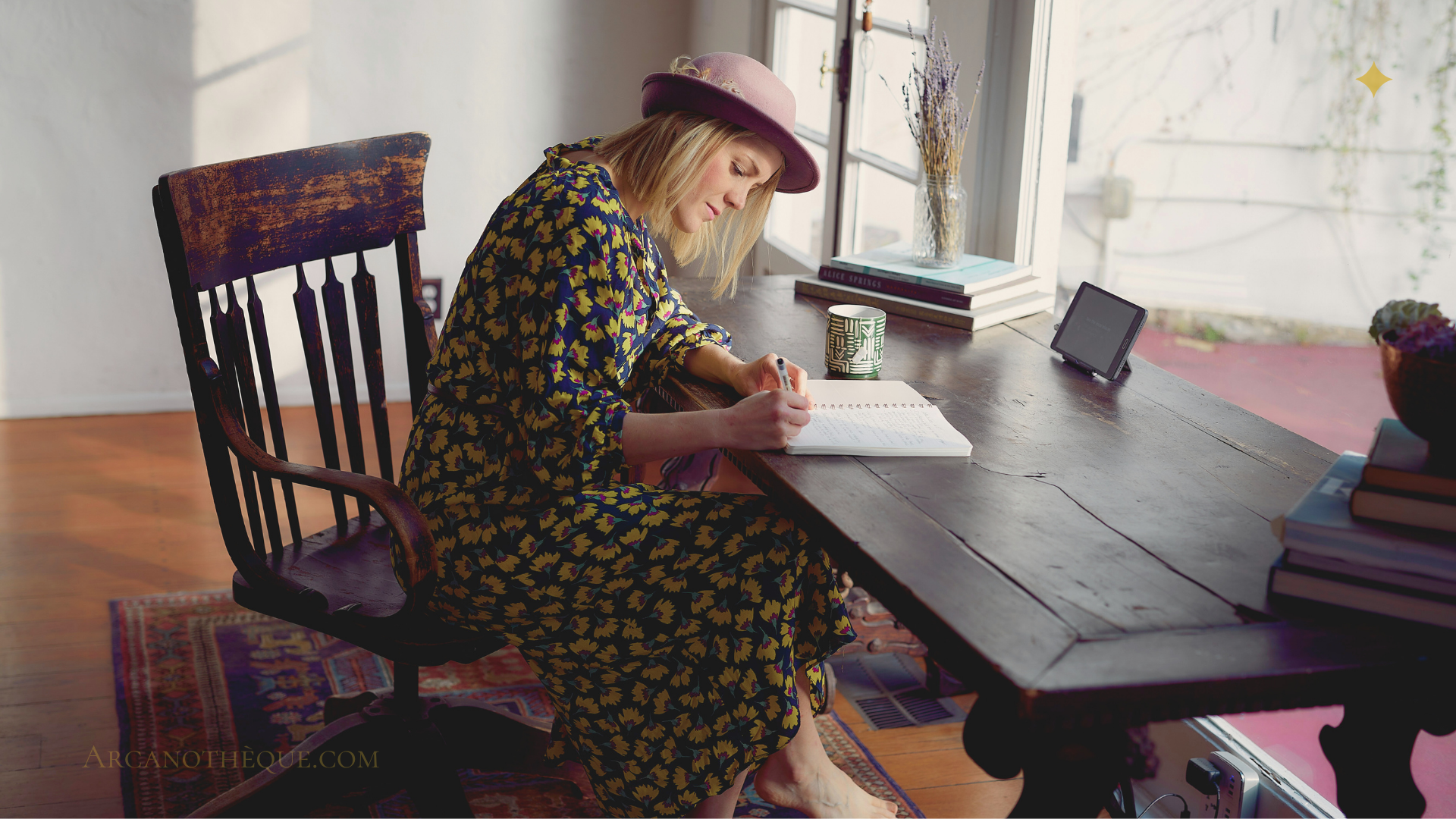 photo d'une femme assise devant un bureau qui écrit sur un carnet, elle a une robe à fleurs jaune et porte un chapeau